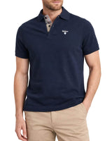 Man wearing a navy blue Barbour polo shirt with a brand logo on a white background
